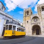 Lisbon city and famous yellow tram 28 in front of Santa Maria cathedral on a sunny summer day. Trams in Lisbon, Portugal. Tourist attraction