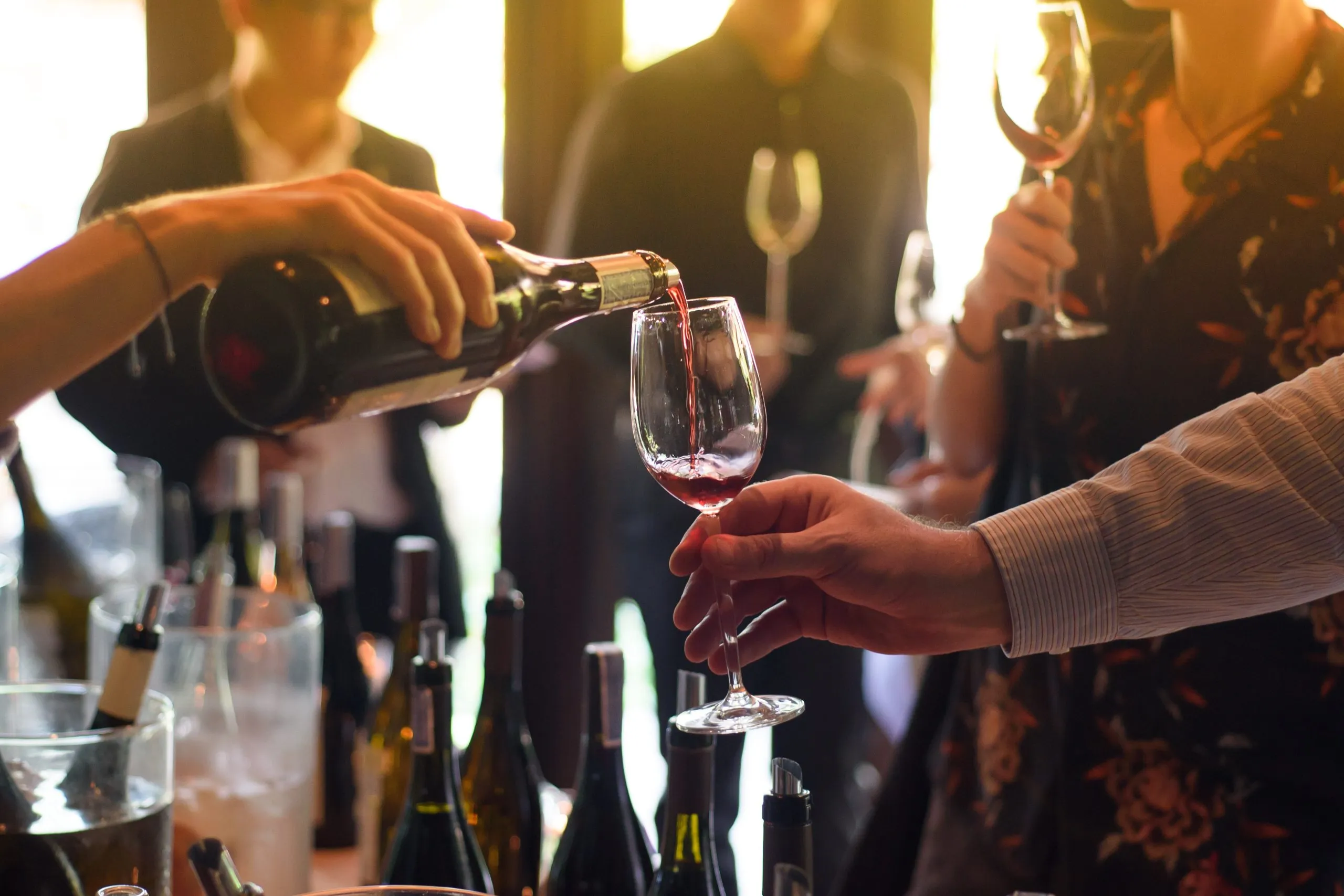 pouring red wine from the bottle into glasses