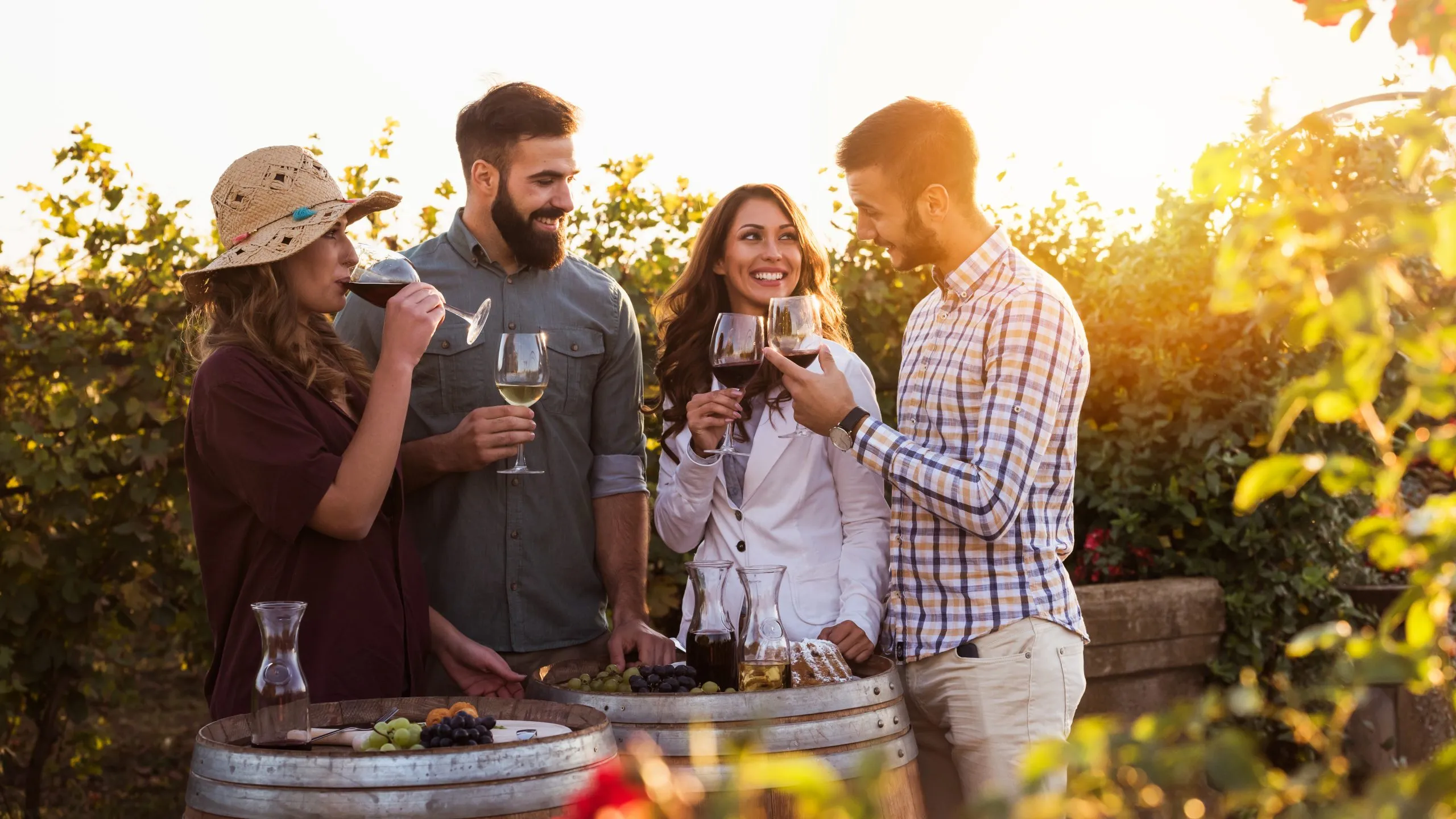 Happy friends having fun drinking wine at winery vineyard - Friendship concept with young people enjoying harvest time together